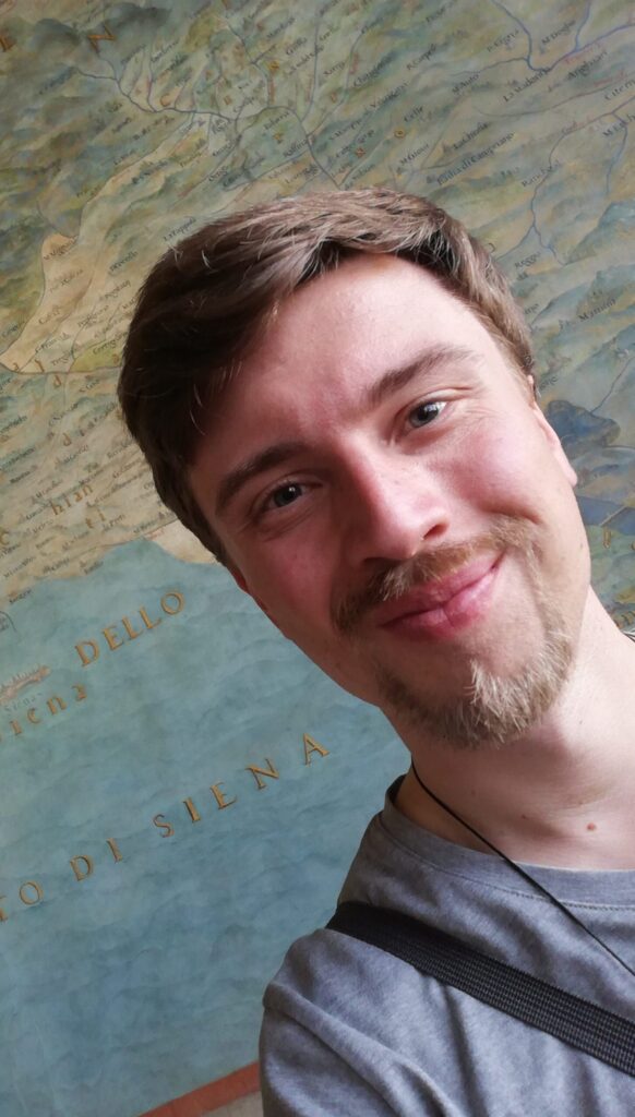Florian Eichhorn steht vor antiker Landkarte und lächelt in die Kamera.